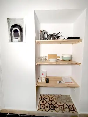 a small kitchen with wooden shelves in a white wall at Apartamentos Casa Vicario in Jerez de la Frontera