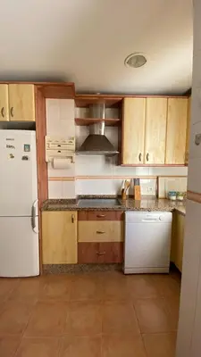 a kitchen with wooden cabinets and a white refrigerator at Puerto Barrio Alto in El Puerto de Santa María