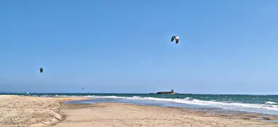 two kites flying over the ocean on a beach at Loft del Capataz in San Fernando
