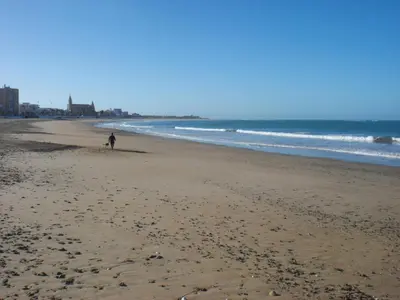 a person walking on a beach near the ocean at Caracola Wohnung in Chipiona