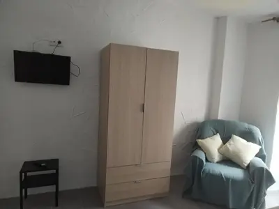 a living room with a blue chair and a cabinet at Apartamentos La Campana 1 in Jerez de la Frontera