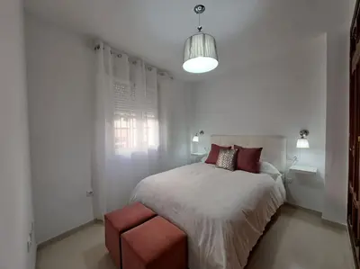 a white bedroom with a large bed and a red stool at Centro de Sanlúcar, La Plata 23 in Sanlúcar de Barrameda