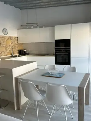 a white kitchen with a table and chairs at Casa Nuna Modern Loft with Private Garden Terrace in Jerez de la Frontera