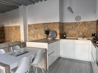 a kitchen with white cabinets and a table with chairs at Casa Nuna Modern Loft with Private Garden Terrace in Jerez de la Frontera