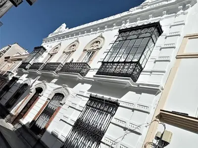 a tall white building with black barred windows at Casa Palacio Argüeso in Sanlúcar de Barrameda