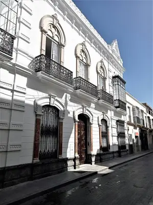 a white building with balconies on a city street at Casa Palacio Argüeso in Sanlúcar de Barrameda