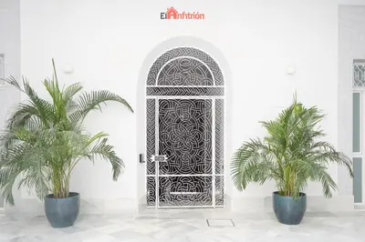 a door in a white room with two palm trees at El Anfitrión - Argüeso apartamento 3 in Sanlúcar de Barrameda