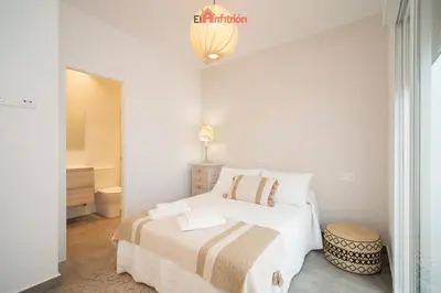 a white bedroom with a bed and a bathroom at El Anfitrión - Argüeso apartamento 3 in Sanlúcar de Barrameda