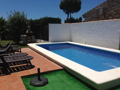 a swimming pool in a yard with chairs next to a fence at Villa El Bomberito in Chiclana de la Frontera