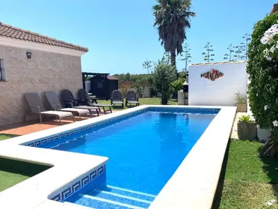 a swimming pool with blue water in a yard at Villa El Bomberito in Chiclana de la Frontera