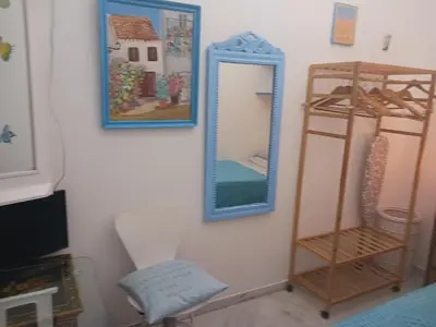 a mirror on a wall with a shelf and a chair at Habitación privada con baño. in Cádiz