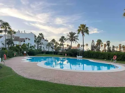 a large swimming pool with palm trees and buildings at GINVA - Costa Ballena & Playa del Infante in Chipiona