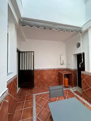 a room with a white table and a chair and a room with a wall at Chipiona Suites A in Chipiona