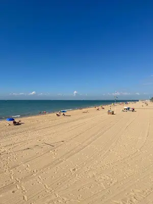 a beach with people sitting on the sand and the ocean at Chipiona Suites A in Chipiona