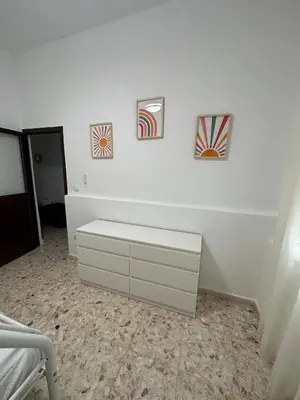 a bedroom with a white dresser and three pictures on the wall at Chipiona Suites A in Chipiona