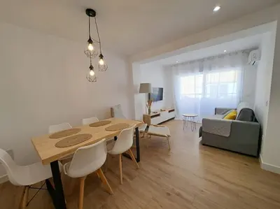 a dining room and living room with a table and chairs at Avda de las Piletas, segunda línea de playa in Sanlúcar de Barrameda