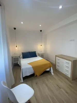 a bedroom with a bed and a desk and a chair at Avda de las Piletas, segunda línea de playa in Sanlúcar de Barrameda