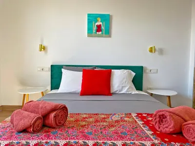 a bedroom with a bed with a red pillow and a rug at Apartamento Ronda de la Luz - Ole Solutions in Jerez de la Frontera