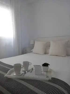 a tray with cups and spoons on a bed at Alegrías de Cádiz by Gades Gestión in Cádiz
