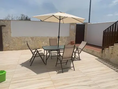 a table and chairs with an umbrella on a patio at Apartamento in Sanlúcar de Barrameda