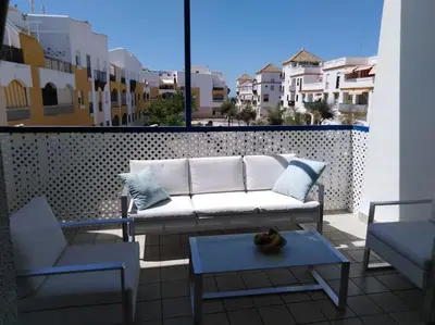 a couch on a balcony with a table and chairs at AMPLIO PISO EN COSTA BALLENA A 100 M DE LA PLAYA in Costa Ballena