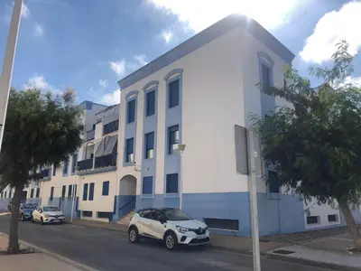 a white building with cars parked in front of it at AMPLIO PISO EN COSTA BALLENA A 100 M DE LA PLAYA in Costa Ballena