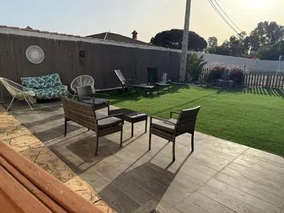 a patio with chairs and a table and a lawn at La Marciana - piscina pista tenis futbol y baloncesto privado - Bungalow externo independiente in Chiclana de la Frontera