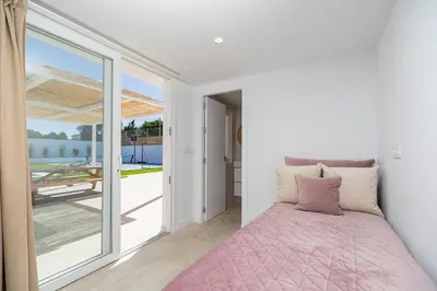 a bedroom with a pink bed and a sliding glass door at Complejoschiclana in Chiclana de la Frontera