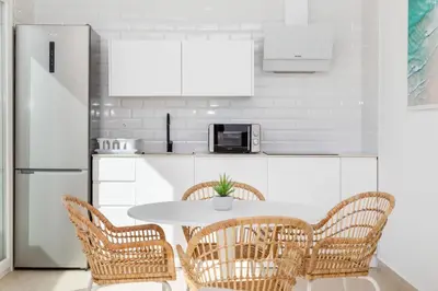 a kitchen with a table with chairs and a refrigerator at Complejoschiclana in Chiclana de la Frontera