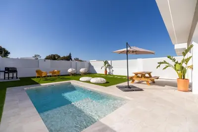 a backyard with a swimming pool and an umbrella at Complejoschiclana in Chiclana de la Frontera
