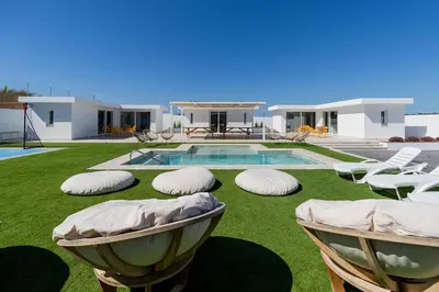 a house with a yard with chairs and a swimming pool at Complejoschiclana in Chiclana de la Frontera