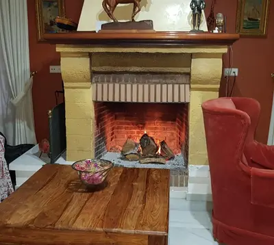a living room with a fireplace with a table and a chair at Casa Mirador del Lago in Arcos de la Frontera