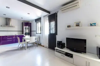 a kitchen with purple cabinets and a table with a tv at Apartamento en el centro a 200 m de la playa in Cádiz