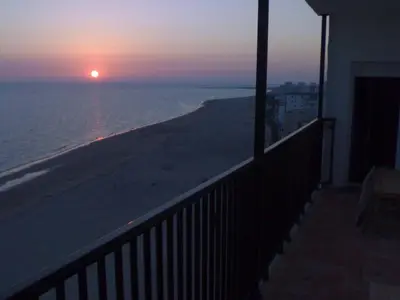 a view of the beach at sunset from a balcony at 1ª Línea de playa, ESPECTACULARES VISTAS, GARAJE, WIFI in Rota
