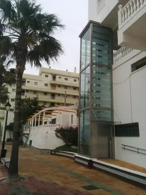 a building with a palm tree in front of it at 1ª Línea de playa, ESPECTACULARES VISTAS, GARAJE, WIFI in Rota
