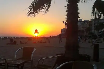 a sunset on the beach with people on the beach at 1ª Línea de playa, ESPECTACULARES VISTAS, GARAJE, WIFI in Rota