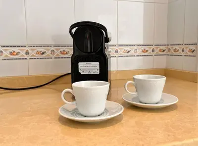 two cups on plates next to a coffee maker at SibsSanlucar Carril SanDiego Centro Familias Garaje in Sanlúcar de Barrameda
