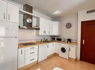 a kitchen with white cabinets and a washer and dryer at SibsSanlucar Carril SanDiego Centro Familias Garaje in Sanlúcar de Barrameda