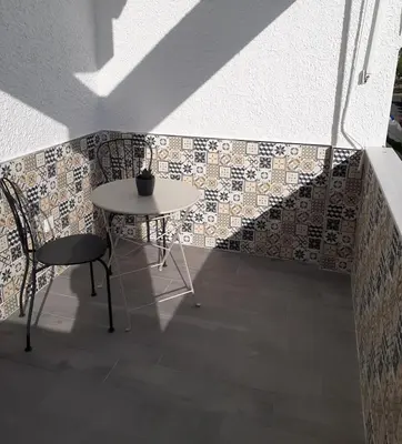 a table and chair next to a wall with tiles at Apartamento Rota in Rota
