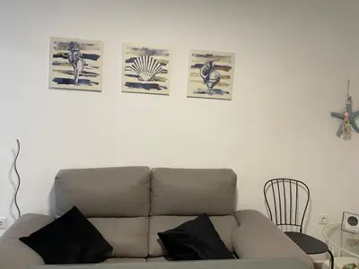 a living room with a couch and four pictures on the wall at Apartamento Rota in Rota