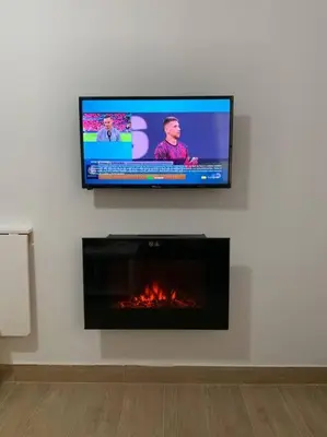 a flat screen tv on a wall with a fireplace at CASITA PINYPON in Jerez de la Frontera