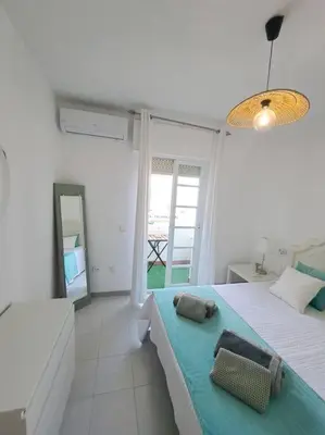 a white bedroom with a bed and a mirror at Dúplex en primera línea de playa 15 in Sanlúcar de Barrameda
