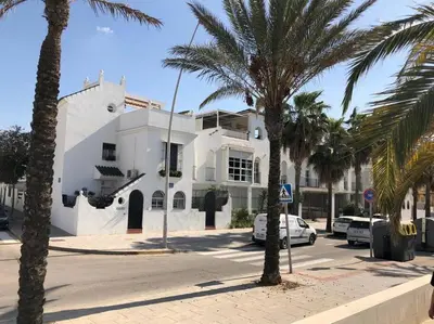 a white building with palm trees in front of a street at Dúplex en primera línea de playa 15 in Sanlúcar de Barrameda
