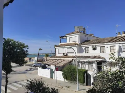 a white building with a parking lot next to the ocean at Dúplex en primera línea de playa 15 in Sanlúcar de Barrameda