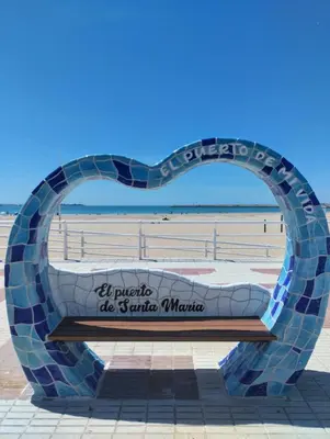 a bench in front of the beach at Apartamento Puertomar in El Puerto de Santa María