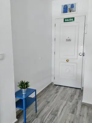 a hallway with a blue table and a white door at Apartamento Puertomar in El Puerto de Santa María