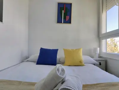 a bedroom with a white bed with blue and yellow pillows at Apartamento Puertomar in El Puerto de Santa María