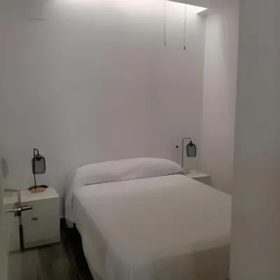 a white bedroom with a bed and two night stands at Castelar in Rota