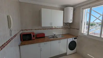 a kitchen with white cabinets and a sink and a microwave at Viva Piso Jerez in Jerez de la Frontera