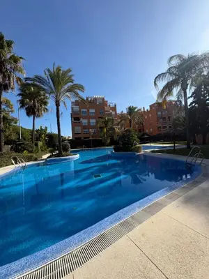 a large swimming pool with palm trees and buildings at Áncora apartamento in El Puerto de Santa María